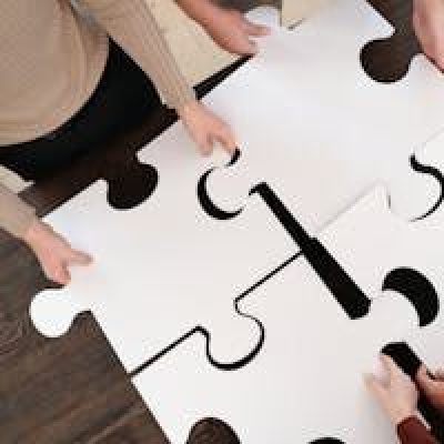 Group collaborating on assembling large puzzle pieces symbolizing teamwork and unity.
